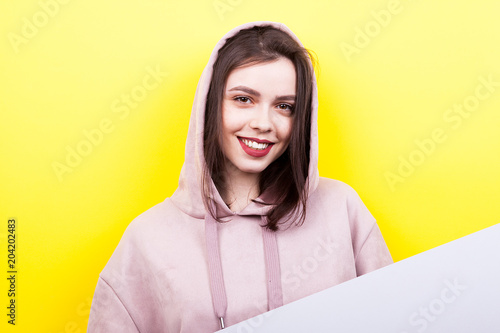 Beautiful smiling woman wearing a hood and holds a banner on yellow background © DC Studio