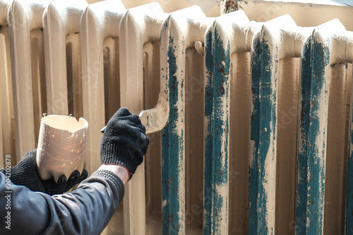 worker paints the metal water heating radiator