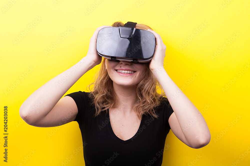 Woman with a VR virtual reality headset on her head on yellow background in studio photo