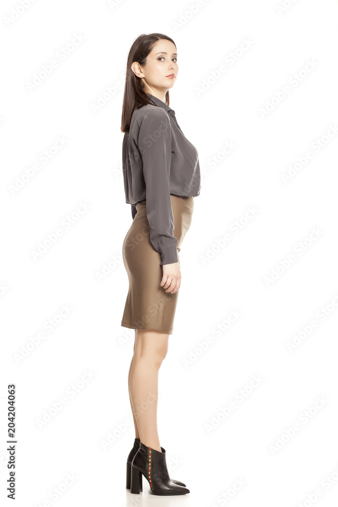 Profile of young businesswoman in skirt, shirt and boots standing on white background Profile of young businesswoman in skirt, shirt and boots standing on white background