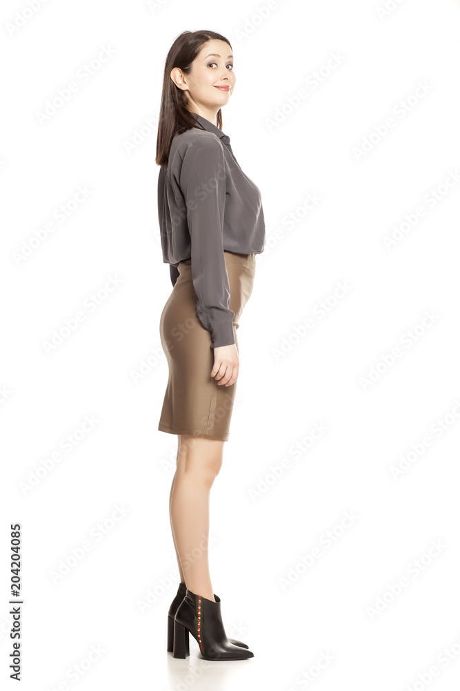 Profile of young businesswoman in skirt, shirt and boots standing on white background Profile of young businesswoman in skirt, shirt and boots standing on white background
