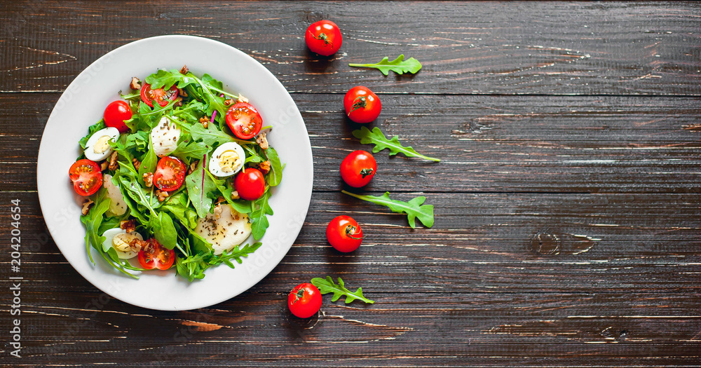 Fresh salad with tomatoes, mixed greens ,nuts, eggs, on wooden background . Healthy food. Fresh salad with tomatoes, mixed greens ,nuts, eggs, on wooden background . Healthy food.