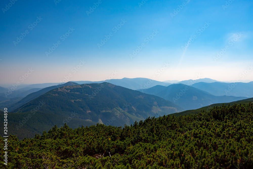 Obraz premium Wooded hills and green valleys under blue sky