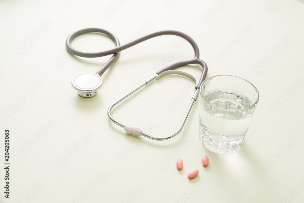 colored pills and a glass of water and stethoscope colored pills and a glass of water and stethoscope