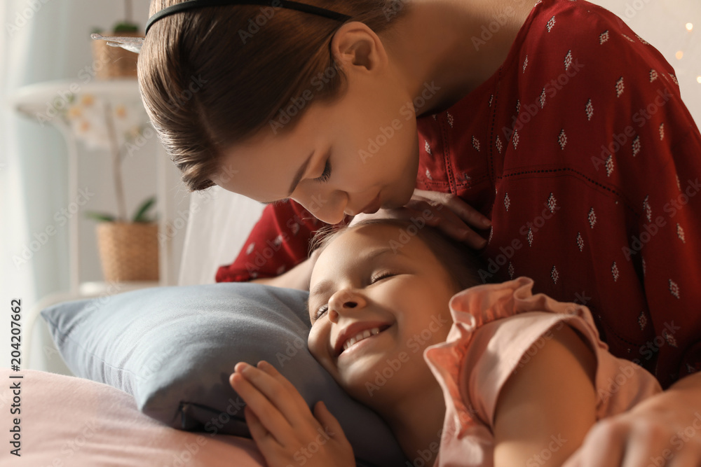 Mother kissing her cute sleepy daughter at home Mother kissing her cute sleepy daughter at home