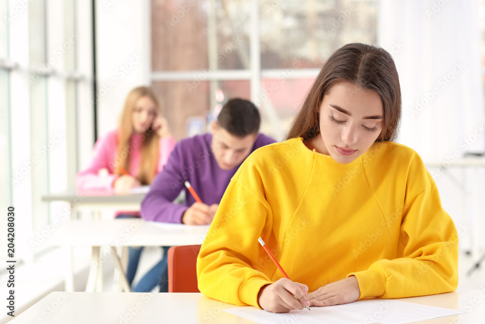 Student writing test to pass exam in classroom