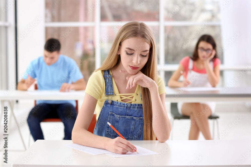 Student writing test to pass exam in classroom Student writing test to pass exam in classroom