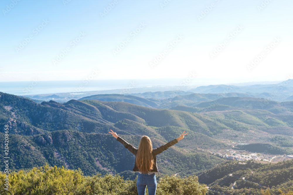 Beautiful women showing peace sign while enjoying mountains landscape