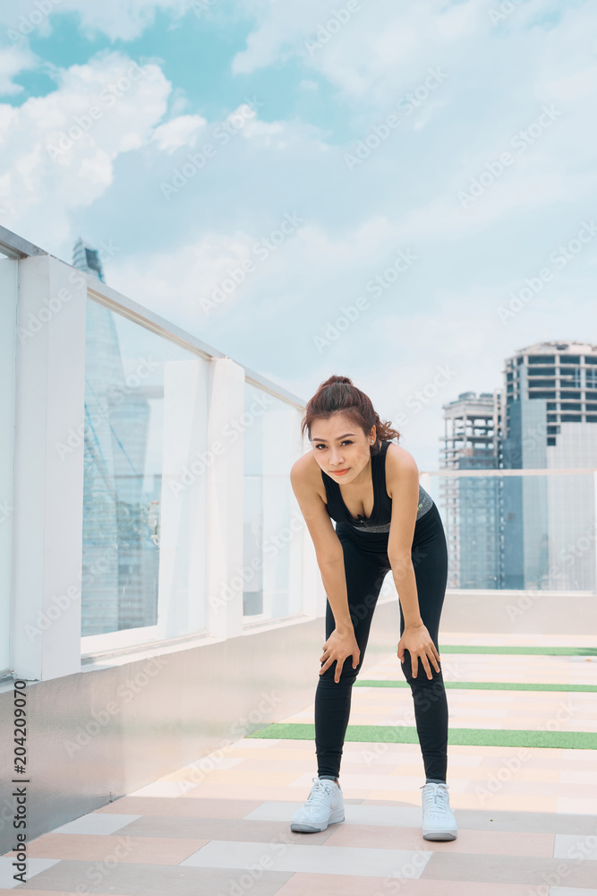 Obraz premium Tired asian woman runner taking a rest after running