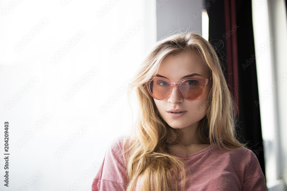 Beautiful girl in sunglasses with natural light. next to the window Beautiful girl in sunglasses with natural light. next to the window