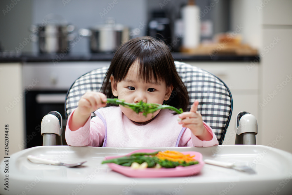 Baby girl eating healthy vegetable at home Baby girl eating healthy vegetable at home
