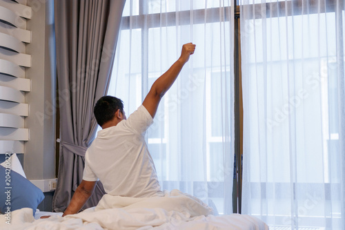 Man stretching in bed after wake up in the morning.
