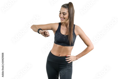 Portrait of smiling young female looking at wrist watch, fitness woman in sportswear, isolated