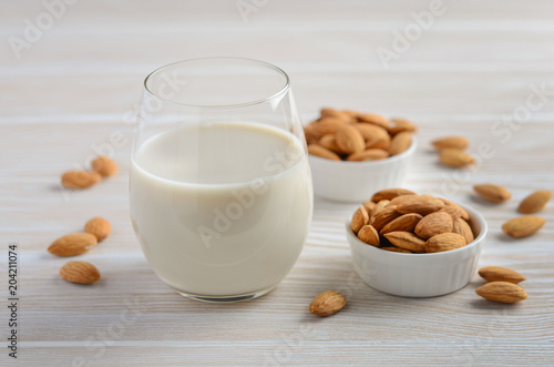 Almond milk and almonds on a white wooden background, selective focus