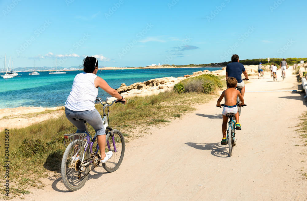 Ibiza, Spain - October 5, 2017 : View of road with car and bicyclist riding on pear. Big green palm tree on Ibiza and Formentera island beach. Summer holidays and free time at sunny weather near sea.