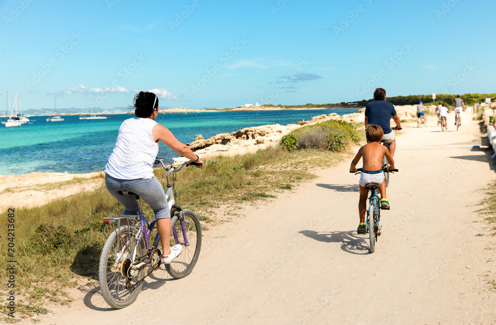 Fototapeta premium Ibiza, Spain - October 5, 2017 : View of road with car and bicyclist riding on pear. Big green palm tree on Ibiza and Formentera island beach. Summer holidays and free time at sunny weather near sea.