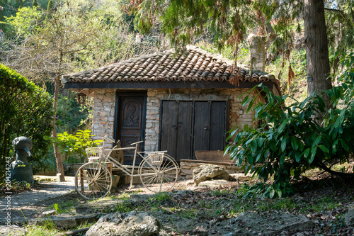 Konstfotografi Stone house with a retro white wheel in front