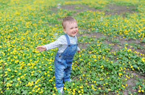 Beautiful little boy on a meadow with yellow flowers dandelions on the nature in the city park