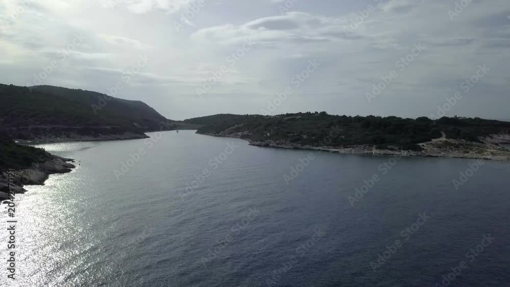 Aerial: Flying over beautiful bay on island Vis in Croatia at evening. Sun reflecting from blue sea water. Filmed on sailing trip in Adriatic sea in Croatia. Aerial: Flying over beautiful bay on island Vis in Croatia at evening. Sun reflecting from blue sea water. Filmed on sailing trip in Adriatic sea in Croatia.