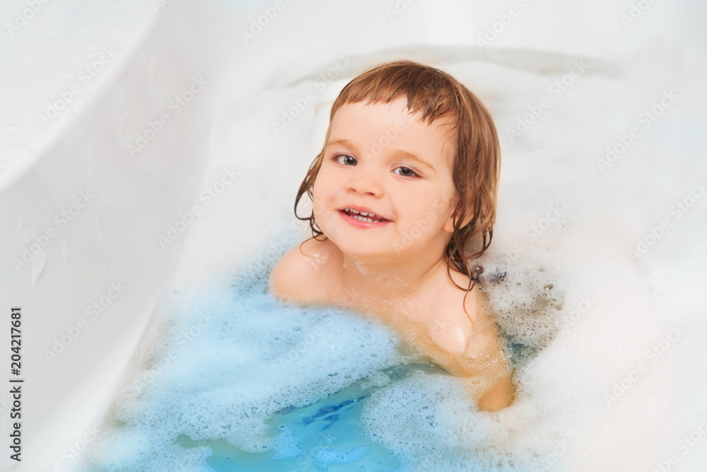 Funny child playing with water and foam in a bathroom. child bathes. Funny child playing with water and foam in a bathroom. child bathes.