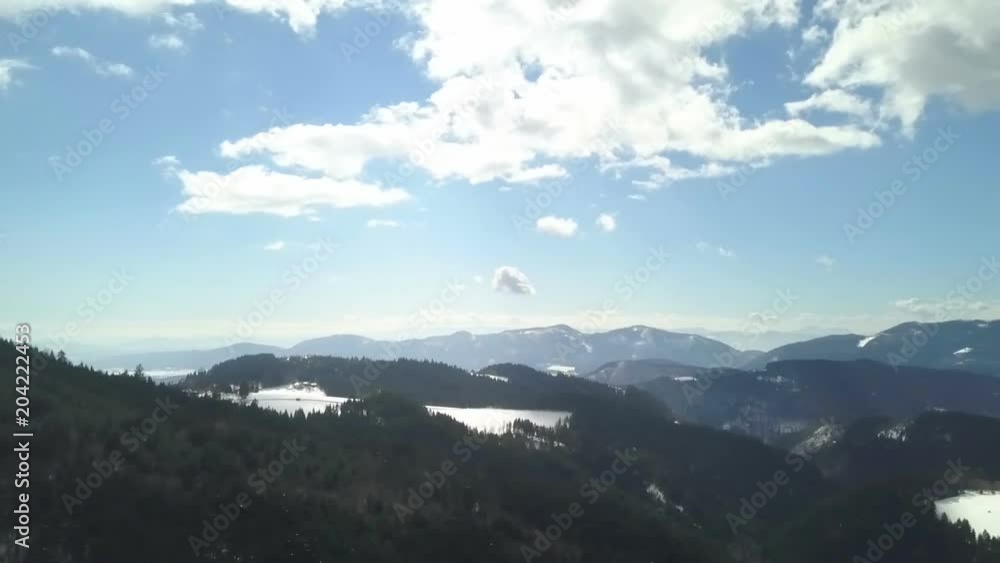There is a beautiful view from the top of a hill. The sun is shining and snow is still covering beautiful slopes. There is a beautiful view from the top of a hill. The sun is shining and snow is still covering beautiful slopes.