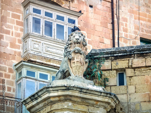 Quiet streets of the capital of Malta - Valletta. The statue of Lion holding a shield on the corner of Lvant Street and Archbishop Street. photo