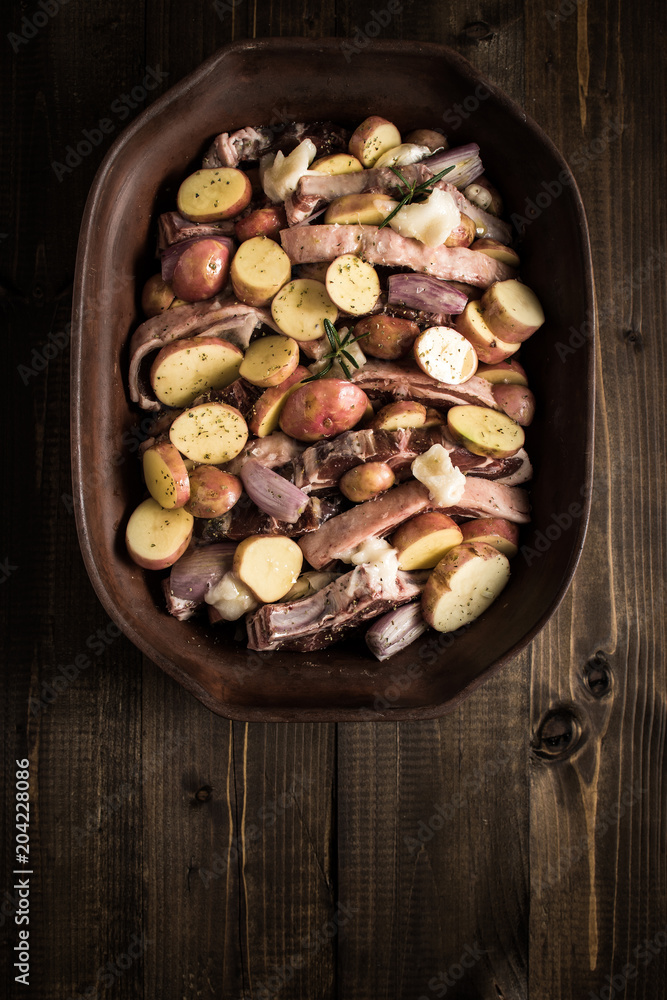 Lamb Loin Chops with Vegetables in Rustic Clay Dish Prepared for Roasting. Copy Space. Lamb Loin Chops with Vegetables in Rustic Clay Dish Prepared for Roasting. Copy Space.