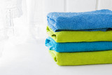stack of clean bath-colored multicolored towels for the bathroom and a basket with towels twisted against a light background