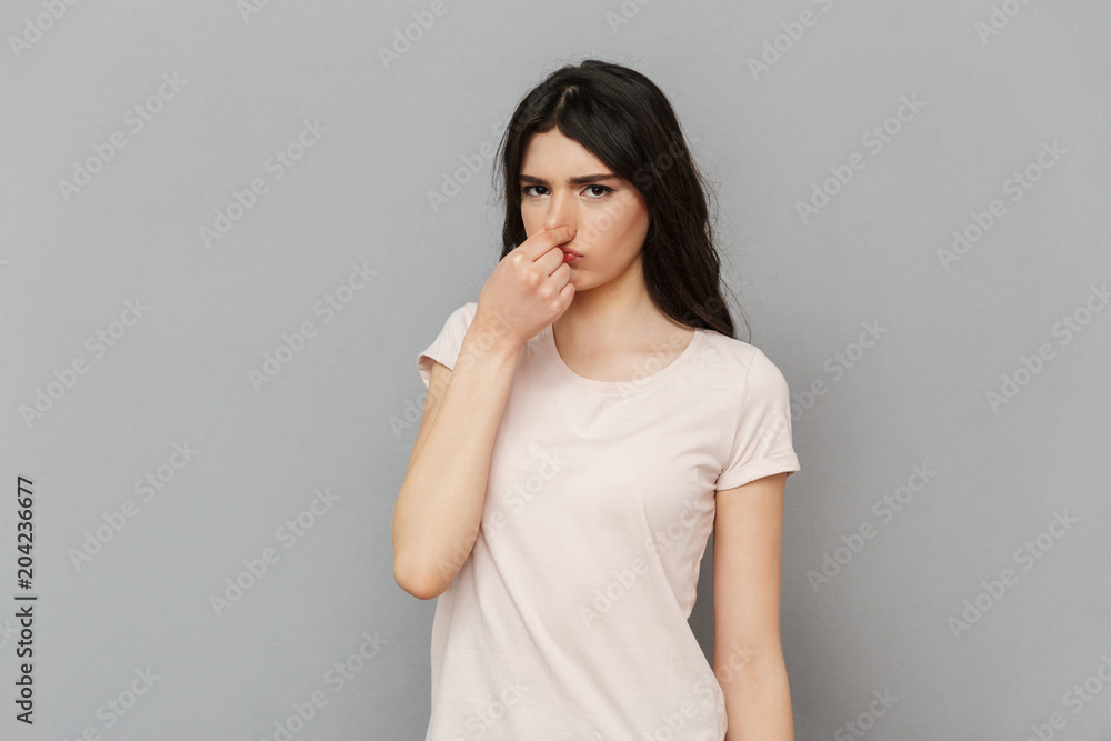 Displeased young lady covering his nose. Displeased young lady covering his nose.