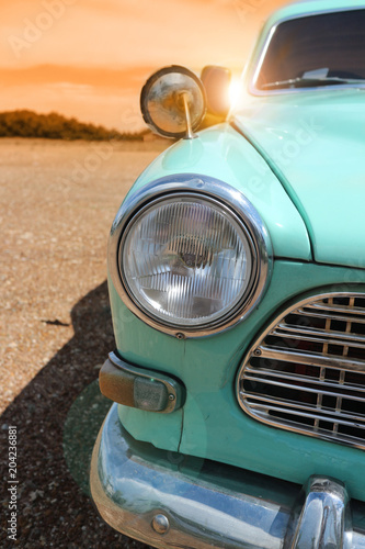 Headlight of a vintage classic old car in the autumn golden sky at sunset time.