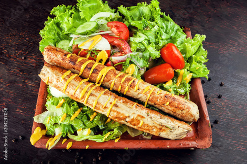 Grilled sausage with vegetables and mostard on wooden board photo