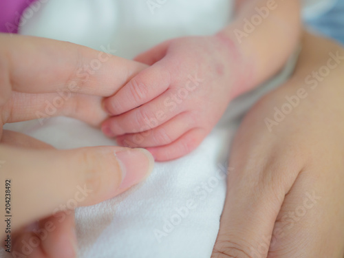 mother day and new born concept from mother's hand hold with small baby foot and hand with soft focus background