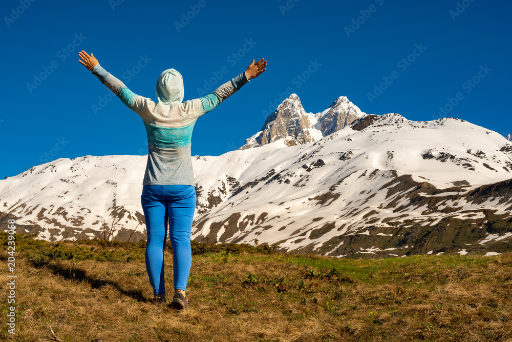 Obraz premium Happy woman, with open arms, admiring the rocky peak