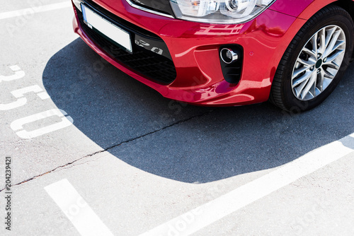 Close-up view of red car on street parking lot