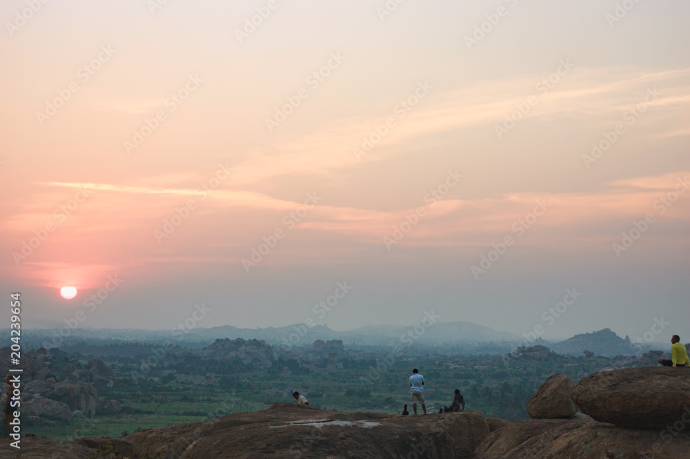 Picturesque view from the Malyavanta Hill at sunset overcast sky in Hampi, Karnataka, India. Tourists enjoy and photograph the sunset