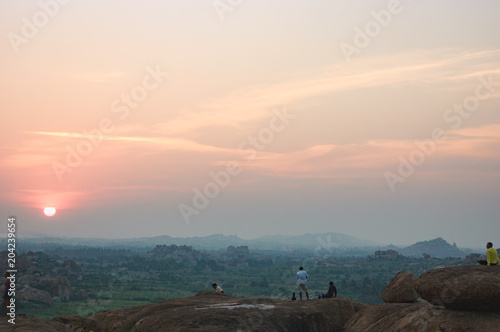Picturesque view from the Malyavanta Hill at sunset overcast sky in Hampi, Karnataka, India. Tourists enjoy and photograph the sunset photo