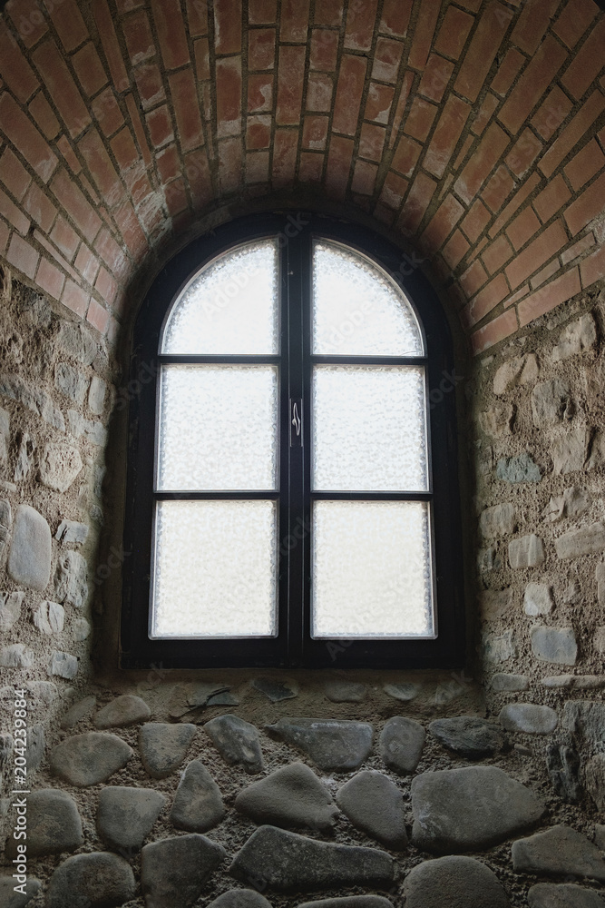 Arched window on the wall of the medieval fortress