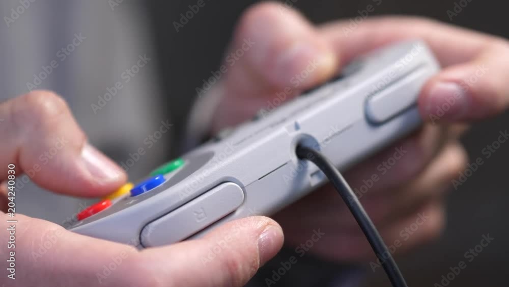 Closeup of hands playing on a retro gaming console controller, pressing the buttons. Closeup of hands playing on a retro gaming console controller, pressing the buttons.