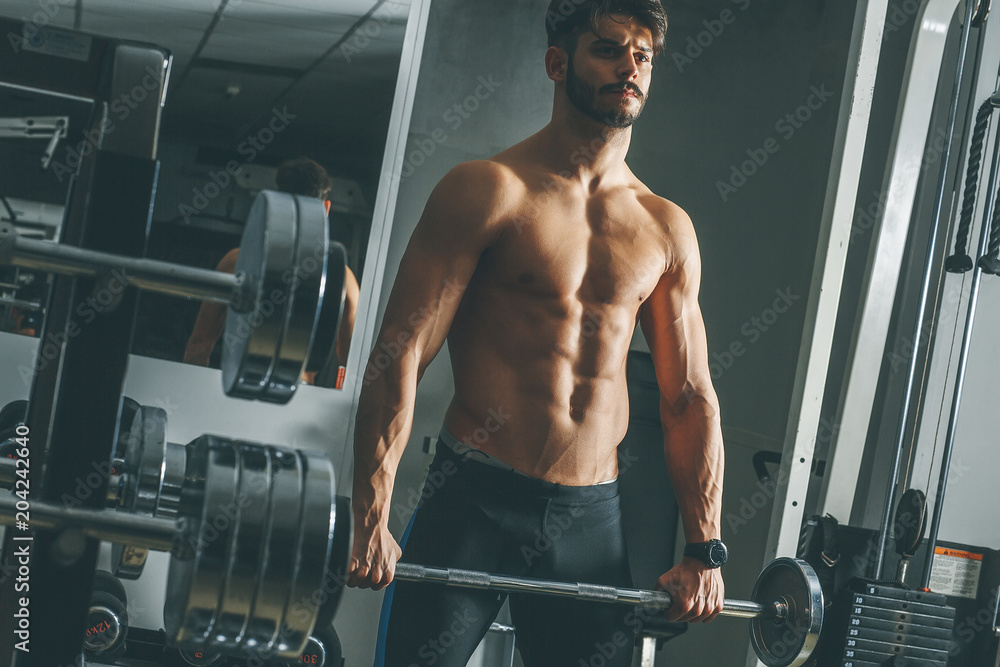 Fototapeta Strong and handsome young man doing exercise with dumbbells