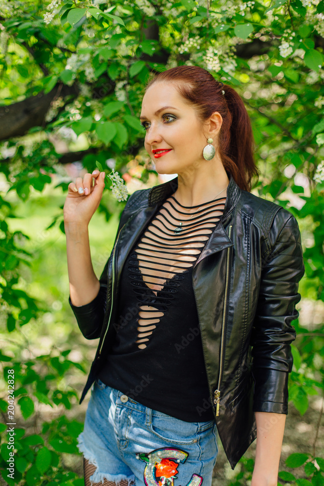 Charming woman dressed in a leather jacket with bird-cherry tree flower