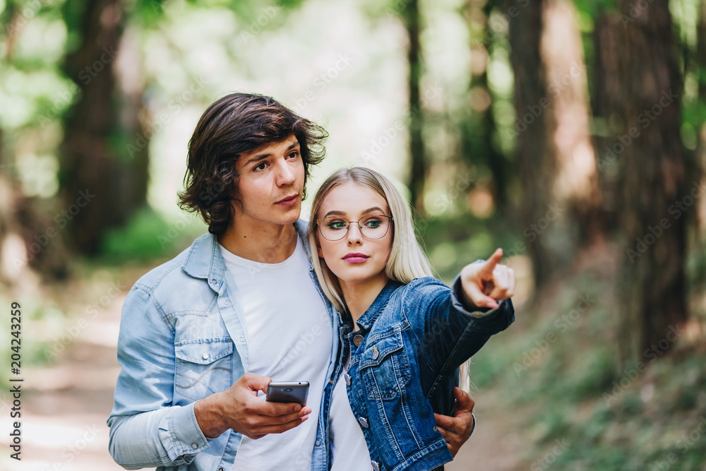 Obraz premium Young couple on adventure in forest using GPS on smartphone as orientation