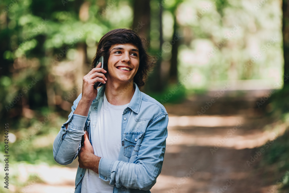 Young man talking on phone while standing in forest