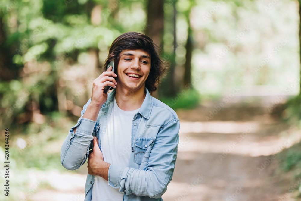 Young man talking on phone while standing in forest Young man talking on phone while standing in forest