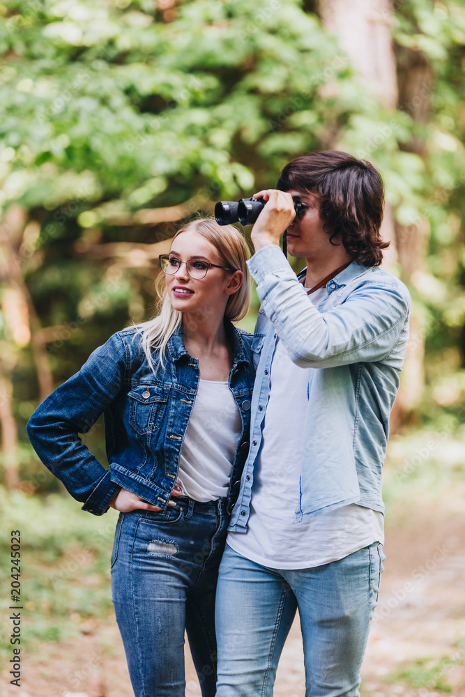 Young couple walking through nature and using binoculars