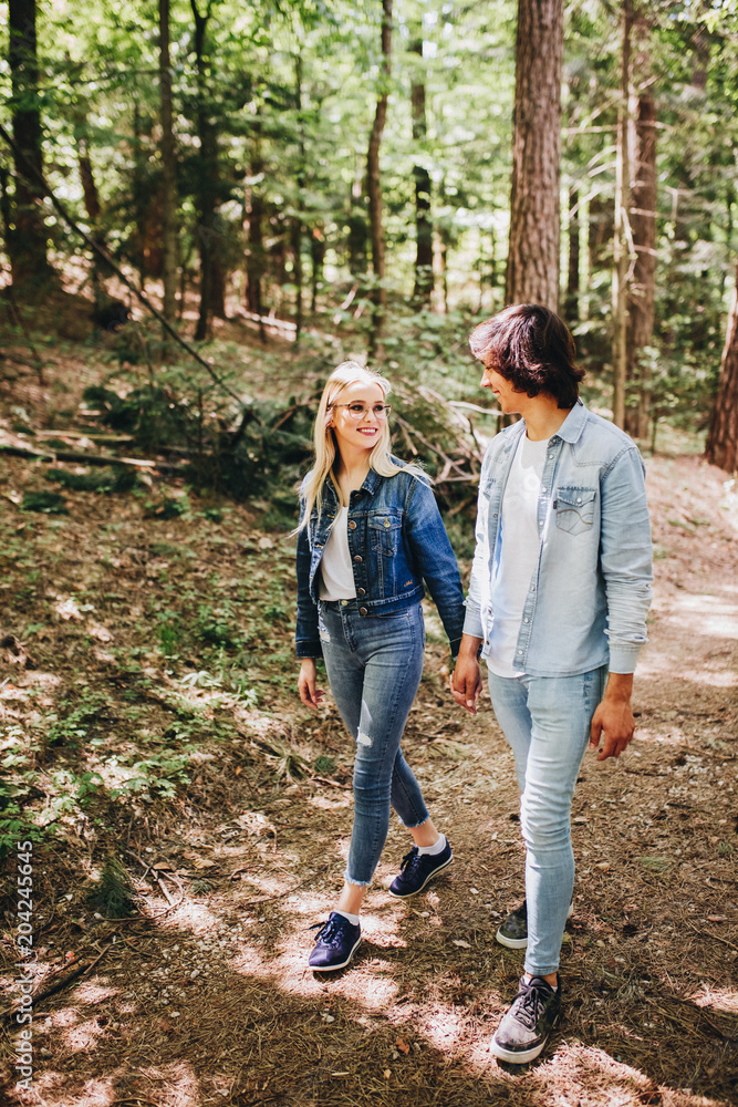Obraz premium Young couple walking, hand in hand, through forest