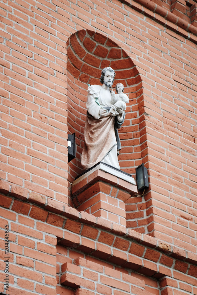 Naklejka premium Religious sculptures on the brick wall, house of the sisters of the Order of Saint Ursula in the historic district of Kamianets-Podilskyi, Ukraine
