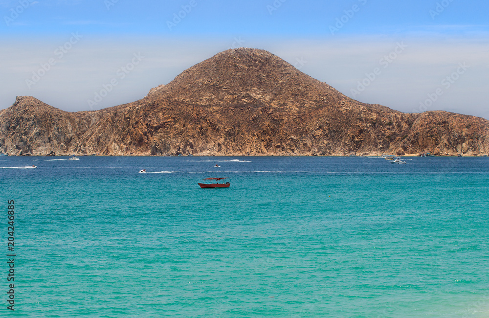 Small red boat in the Mexican ocean overlooking the mountain range