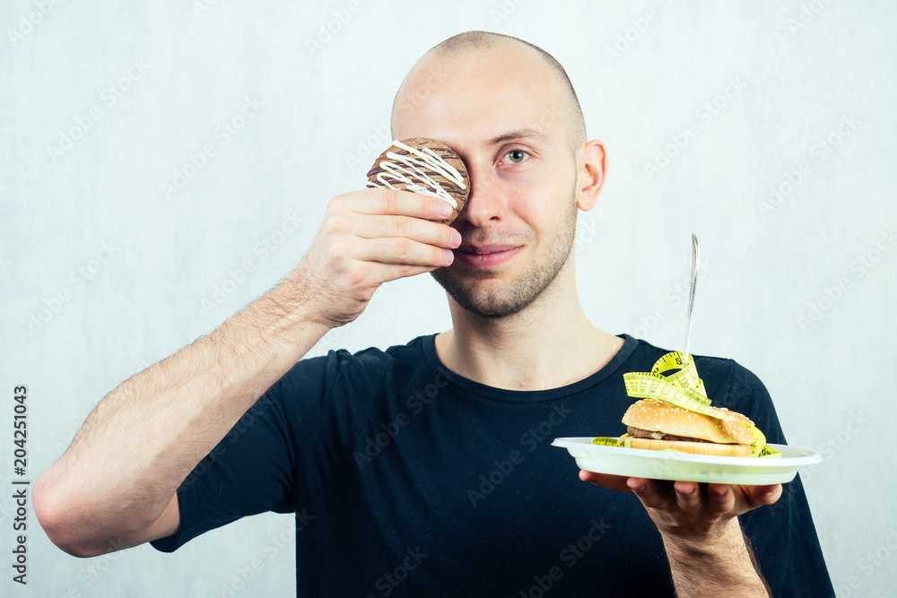 portrait of a young handsome bald hungry man with a measuring tape ...