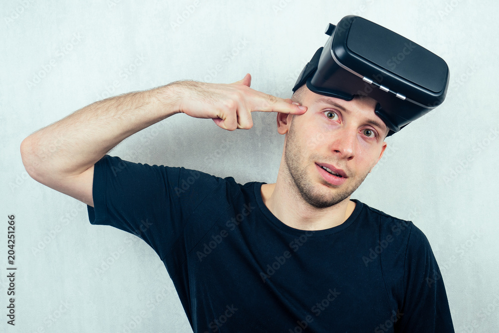Naklejka premium portrait of a young handsome bald man in a mask (glasses) of virtual reality points with his finger. the concept of video games and reality copyspace