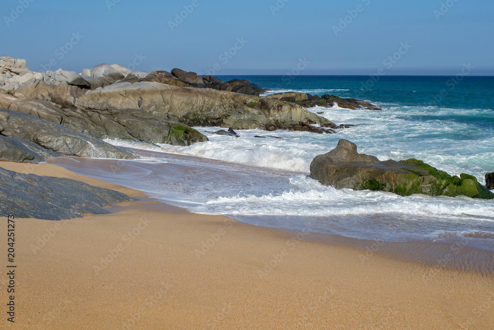 Rocks and small waves on the beach in Mexico